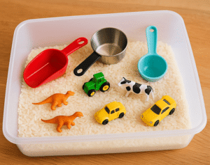 sensory bin for toddlers preschoolers filled with rice, beans, scoops, funnels, and small animal figurines