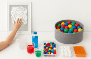 Therapy-inspired sensory activities including shaving cream painting, water pouring stations, ball pit, and sensory walk tubs