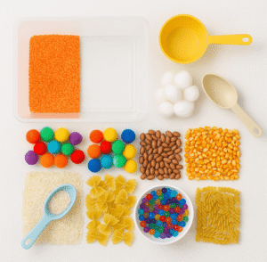 sensory bin starter kit with clear tub, scoops, dyed rice, beans, corn kernels, pasta, pom poms, cotton balls, and colorful water beads