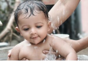 Sensory activities for infants: baby doing water play in shallow basin at home, splashing and exploring with hands
