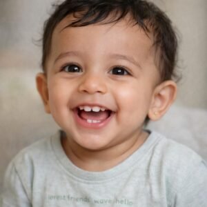 Baby smiling showing two upper central incisor teeth erupted at 9 months