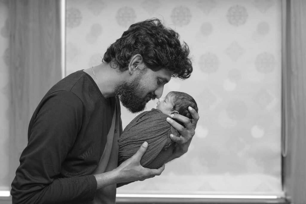 Mom and dad holding newborn baby for first family photo at home
