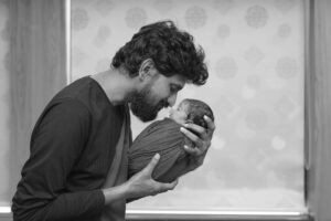 Mom and dad holding newborn baby for first family photo at home