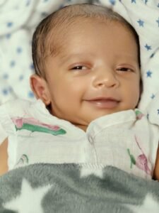 Parent gently lowering a sleeping baby into a crib while the baby begins to wake up