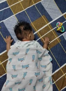 age-by-age guide showing when babies can safely sleep with a blanket from newborn to 18 months
