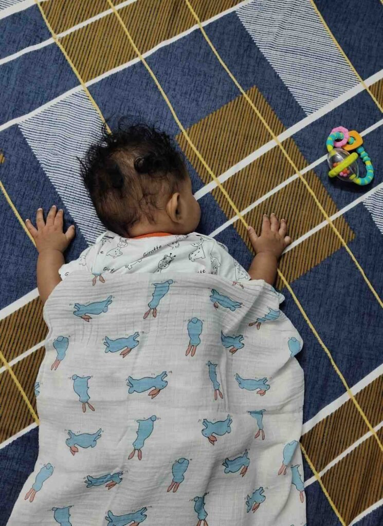 age-by-age guide showing when babies can safely sleep with a blanket from newborn to 18 months